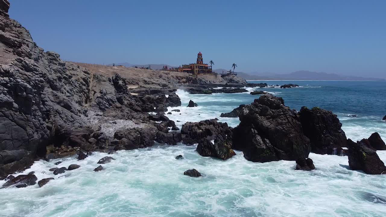 Waves breaking on rugged rocky coastline with clear turquoise water on warm summer day