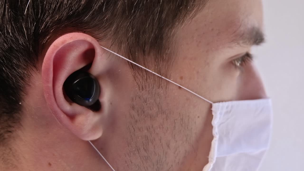 Man wearing a face mask and earbuds