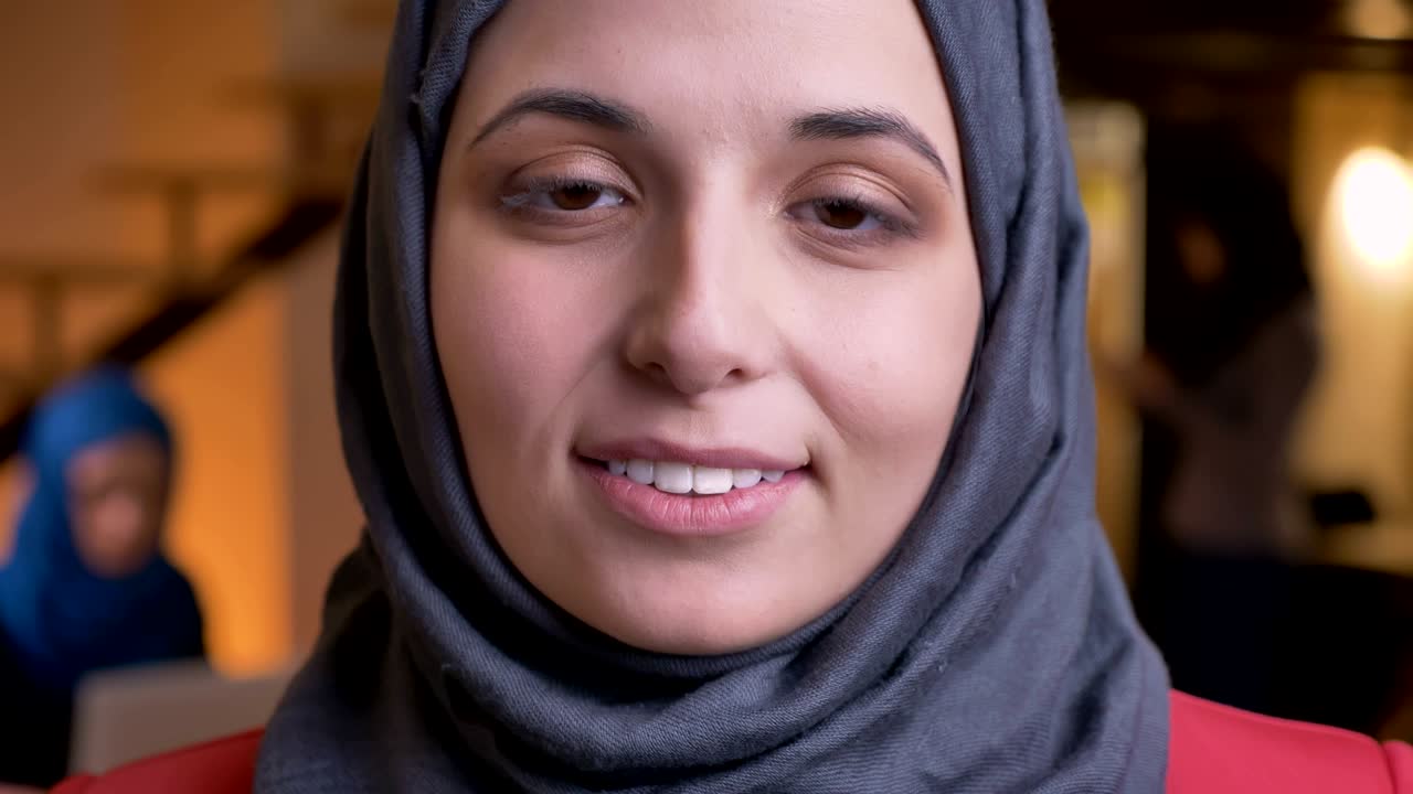 retrato en primer plano de una joven y hermosa mujer árabe con rostro de hijab gris mirando directamente a la cámara con bonitos ojos marrones y expresión facial sonriente
