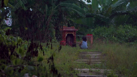 young asian boy at shrine outdoors on a gloomy overcast day chinese prayer site wide shot