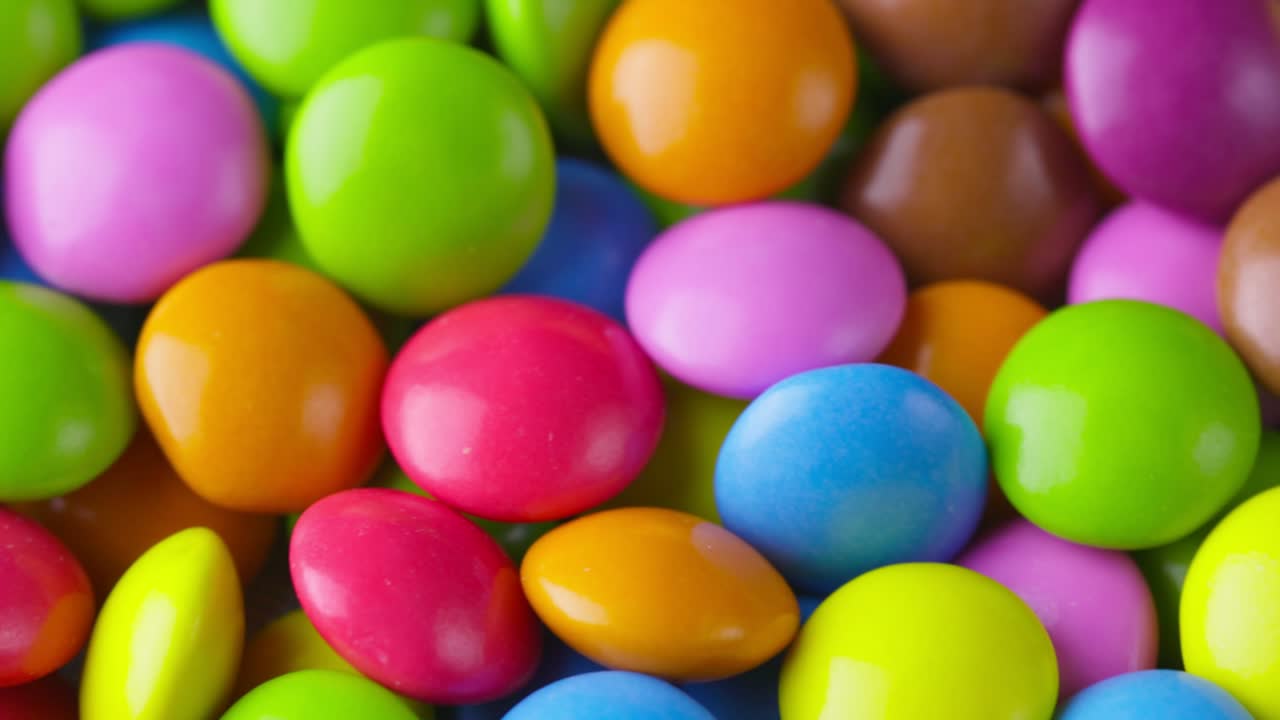 movimiento lento de primer plano de caramelos de chocolate redondos de colores, dragee. rotación y caída de caramellos de chocolate multicolores