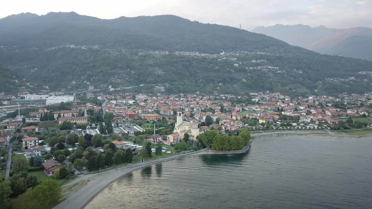 A beautiful drone shot from Dongo in Lake Como, flying towards the picturesque town. The shot captures the charming architecture, serene waterfront, and majestic mountain backdrop.