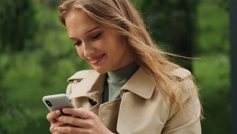 happy caucasian female student using smartphone outdoors.