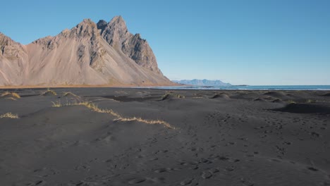 Black-sand-beach-below-sharp-Vestrahorn-mountain-peak-in-Iceland