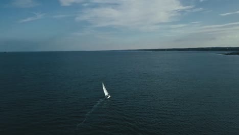 aerial footage of a white sailing boat in an empty ocean in the north sea on a summers day.