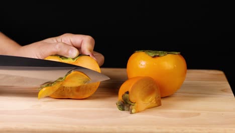 a persimmon being sliced with a knife