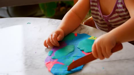 chica linda jugando con arcilla de colores en un hogar cómodo 4k