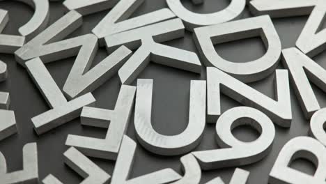 full frame close-up looped rotating background of silver metal letters on flat black surface