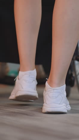 legs of young woman pushing wheelchair with patient with disability on blurred background. nurse takes care of person with paralysis at home closeup