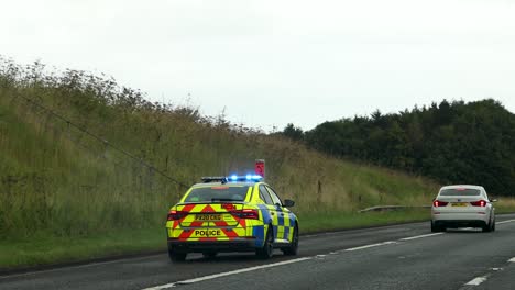 police car with lights on following another vehicle