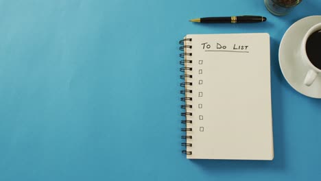 video of notebook with to do list and copy space, coffee and pencil on blue surface