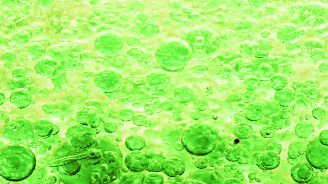 노란색 배경으로 오른쪽에 떠 있는 물 속의 녹색 거품의 매크로 샷