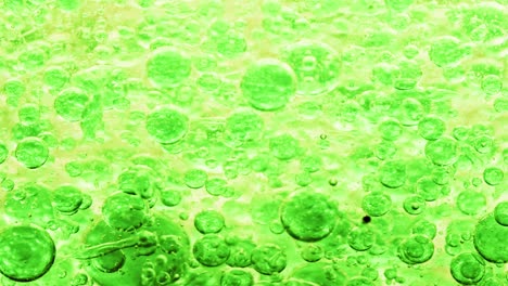 macro shot of green bubbles in water floating right with yellow background