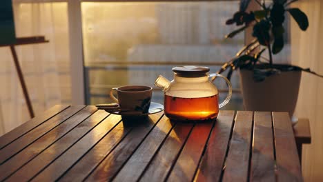 Teapot-and-porcelain-cup-on-table-at-sunset