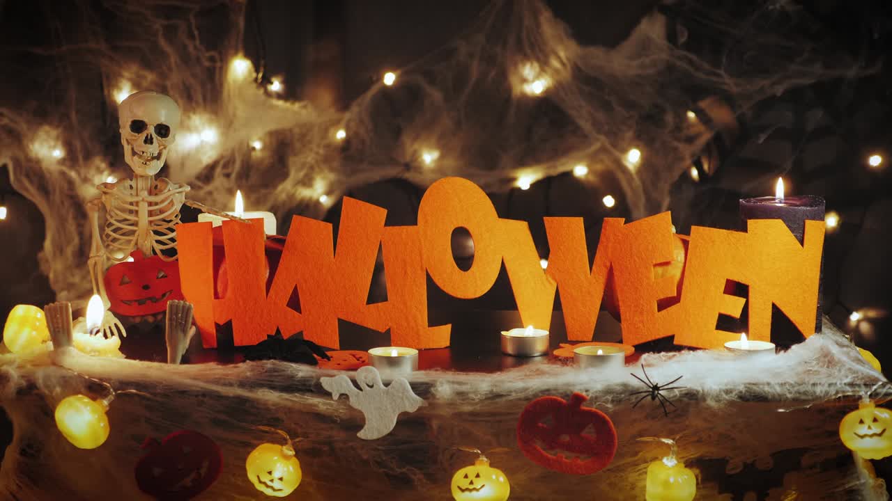 Happy halloween. Celebrating halloween night. Halloween party decorations with pumpkins, cobwebs, spiders and skeleton. Bright orange word Halloween against black scary horror background
