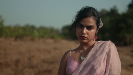 young woman in pink looking contemplative in a rural setting, late afternoon light