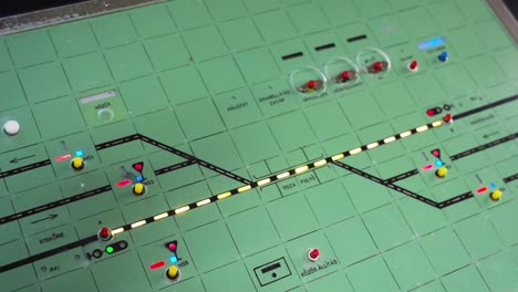 a railway control board with illuminated tracks, signals, and switches for train traffic management