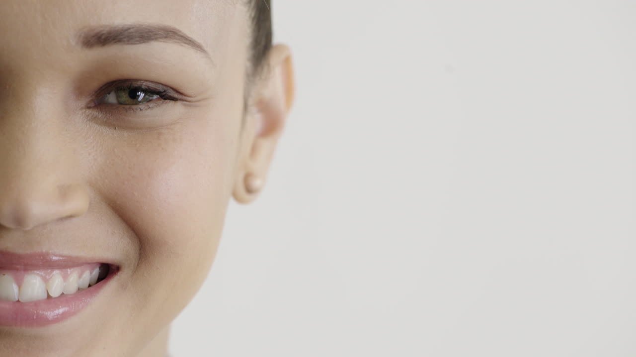 cerca hermosa mujer hispana mitad de la cara sonriendo feliz usando pendientes maquillaje cosméticos sobre fondo blanco