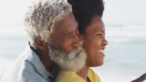 Glückliches-Afroamerikanisches-Paar,-Das-Am-Sonnigen-Strand-Sitzt-Und-Sich-Umarmt