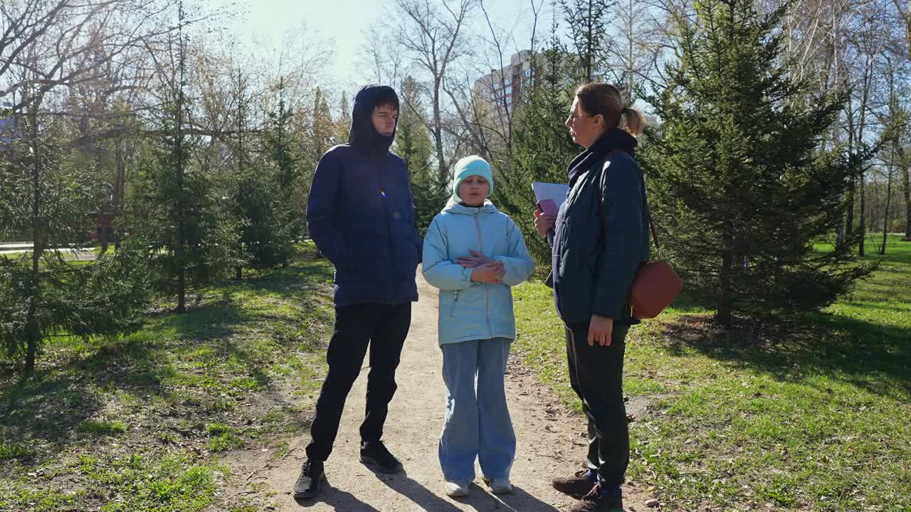 Donna, ragazzo e ragazza che conversano in un parco soleggiato