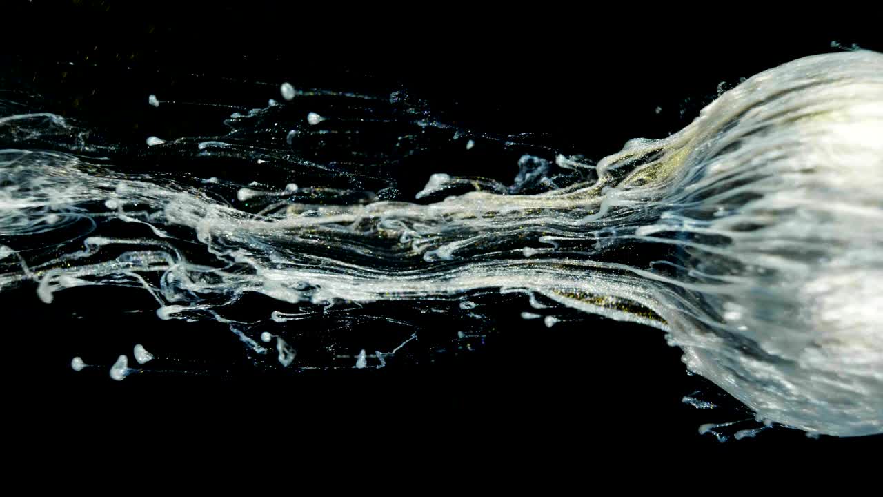 황금빛 빛나는 페인트가 천천히 공에서 흘러나옵니다.