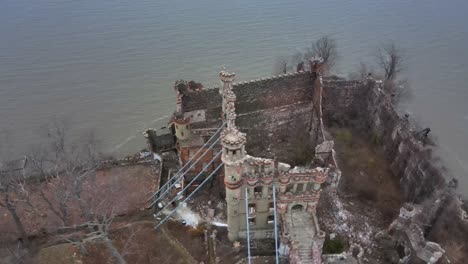 drone footage circling above the ruins of an abandoned castle on an island, showing multiple angles