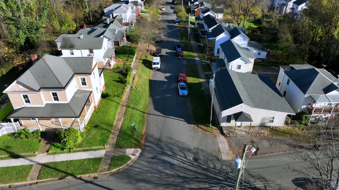 Cyclist on bike turning into street of American neighborhood. Sunny day with foliage tree colors in fall. Aerial top down shot.
