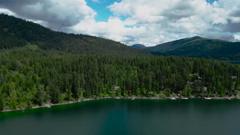 Aerial-video-from-a-drone:-Mountain-lake,-boat-fishing,-pine-forest,-forest-homes-with-docks-in-Canada