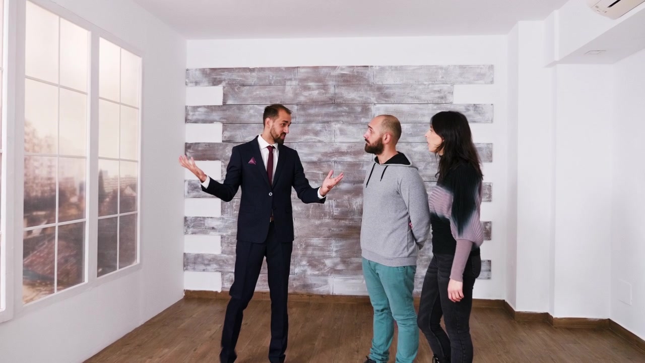 Agent immobilier faisant visiter un appartement vide à un jeune couple