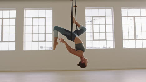 mujer de yoga aéreo practicando una postura de paloma rey con una sola pierna colgada boca abajo usando una hamaca disfrutando de un estilo de vida de acondicionamiento físico saludable haciendo ejercicio en el estudio entrenando meditación al amanecer