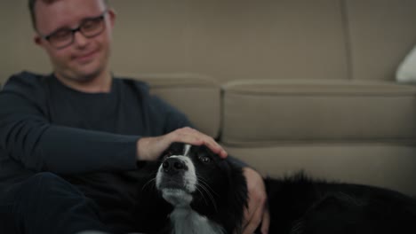 Hombre-Caucásico-Con-Síndrome-De-Down-Sentado-En-El-Suelo-Y-Jugando-Con-Un-Perro-Mascota