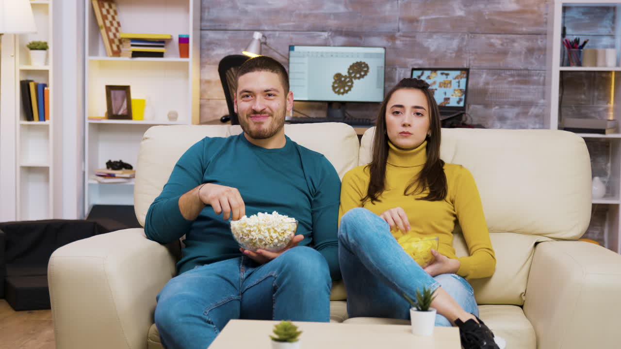 Par, der ser TV og spiser popcorn i stuen
