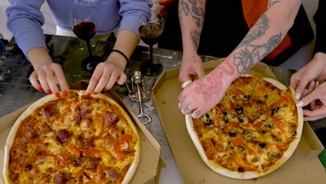 close up of unrecognizable friends sharing pizza at home