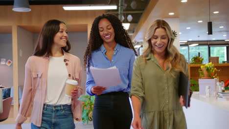 equipo de negocios femenino multicultural con bebidas para llevar caminando por la oficina de plan abierto