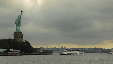 statue of liberty on pedestal in nyc harbor with ferry arriving