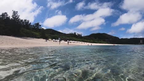 Water-lever-shot-of-tourists-on-serene-beach-on-tropical-island