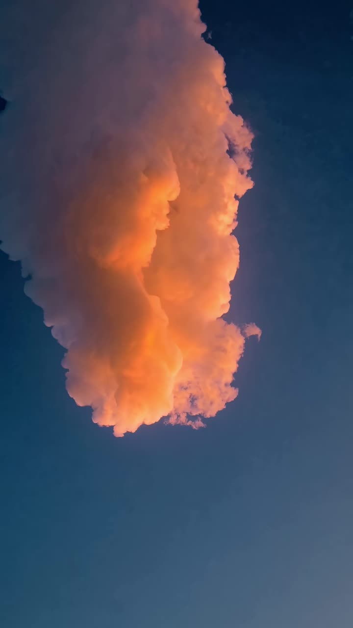 A mesmerizing upward angle captures a glowing pink cloud against a deep blue sky, perfect