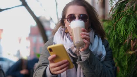woman enjoying a latte and using her phone in a cafe