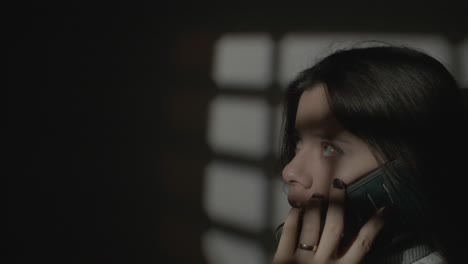 woman making phone call indoors with artistic shadow and light patterns from a window