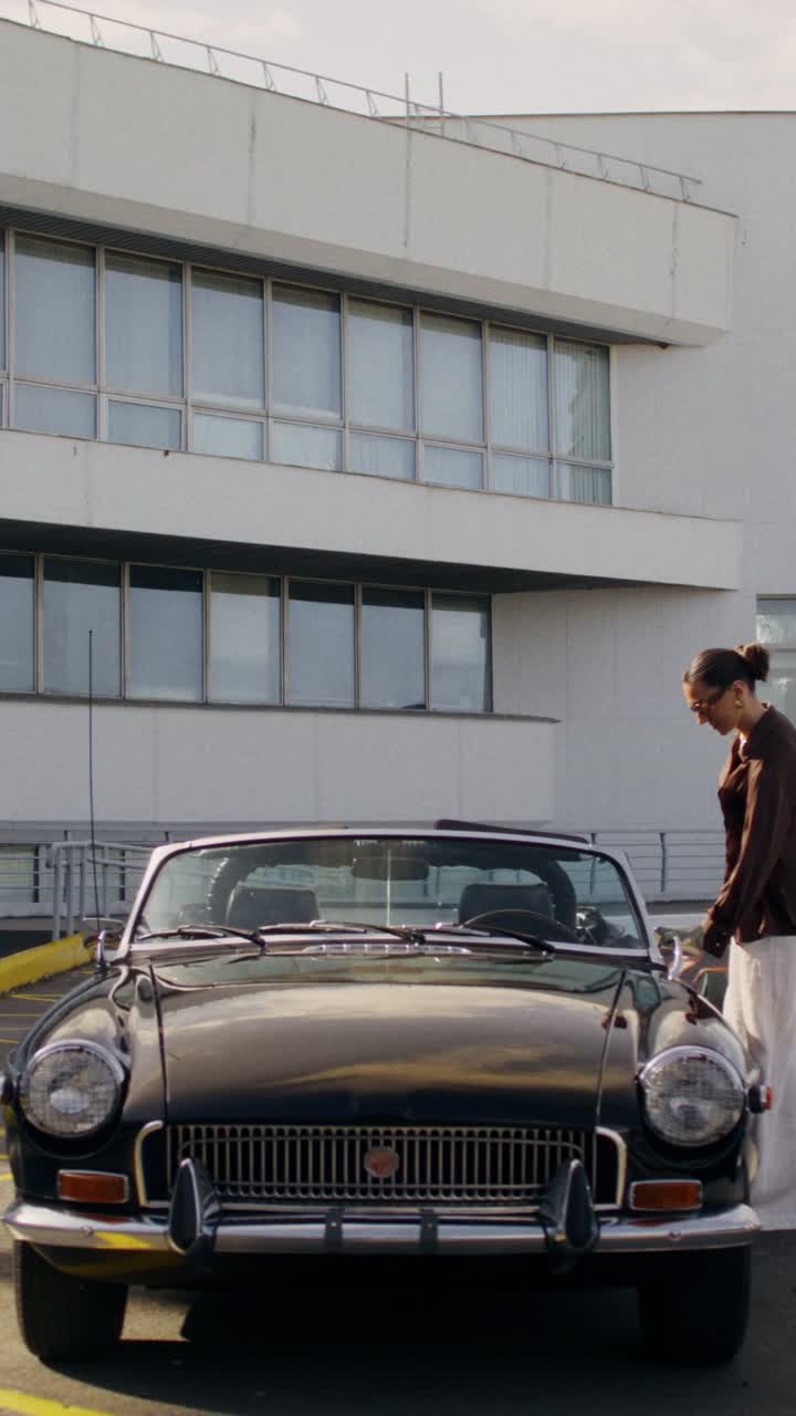 Woman standing by a classic convertible car