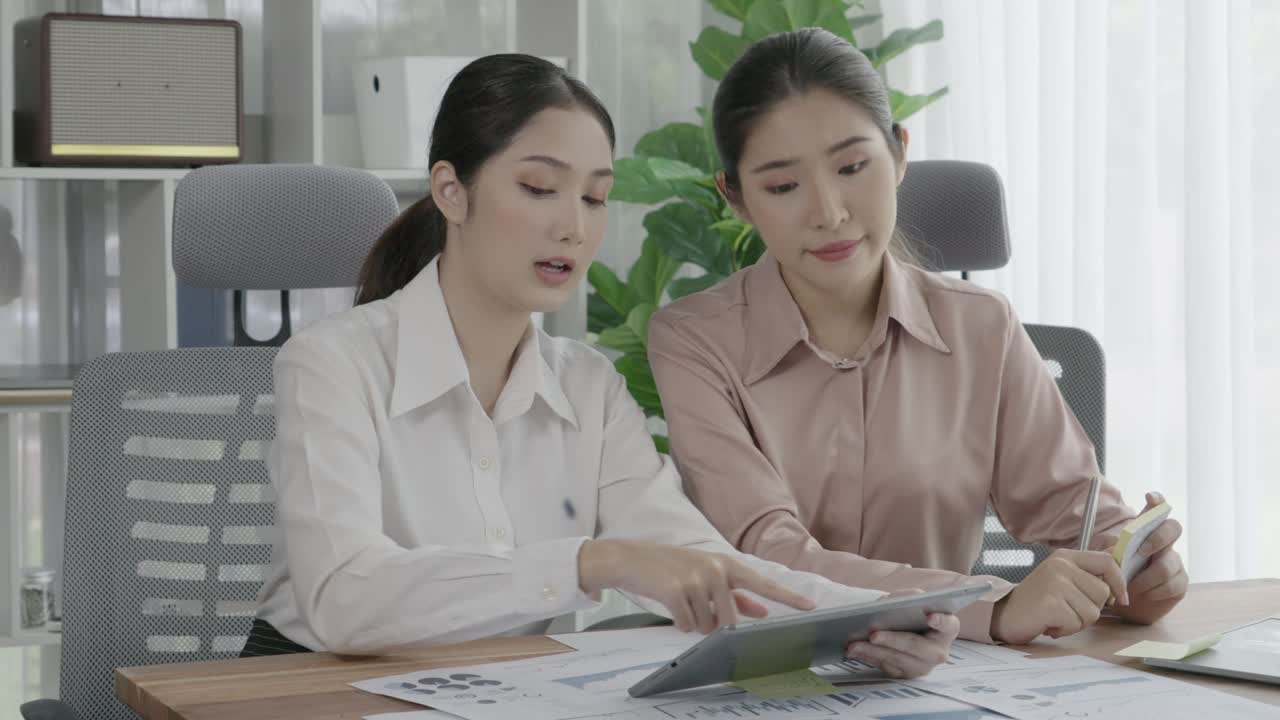 Two young enthusiastic businesswoman working together in the office workspace.