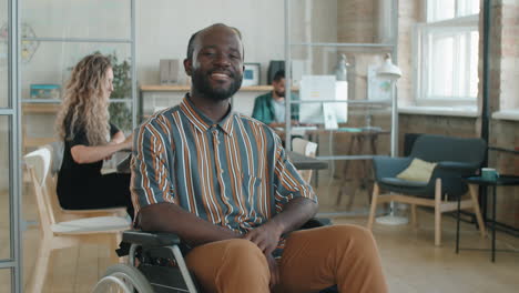 retrato de un alegre hombre de negocios afroamericano en silla de ruedas en la oficina