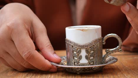 close up of a person holding a turkish coffee cup