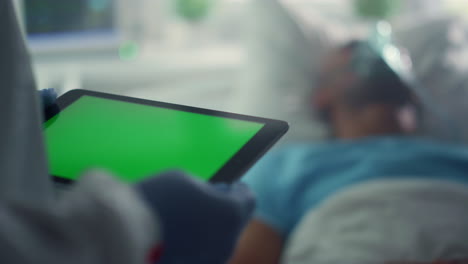 Medizinischer-Mitarbeiter-Hält-Ein-Chroma-Key-Tablet-In-Der-Nähe-Eines-Kranken-Patienten-Im-Krankenhaus,-Nahaufnahme.