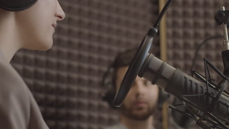 close up of a microphone and a young woman's mouth in the recording studio