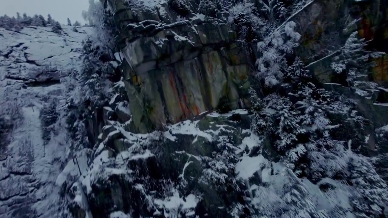 FPV-Drohne gleitet entlang einer schneebedeckten Felswand und zeigt zerklüftetes Gelände am Mont Pinacle.