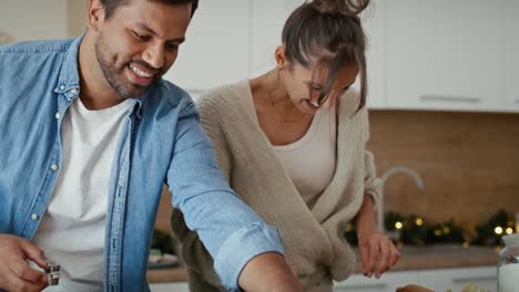 una pareja multiétnica haciendo pan de jengibre en la época de navidad.