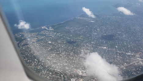 ventana de avión del océano y la playa entrando en una ciudad