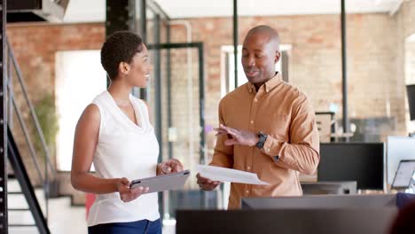 Happy-african-american-colleagues-using-tablet-and-discussing-work-in-office,-slow-motion