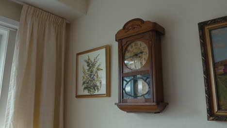 old antique grandfathers clock hanging and ticking on an egg-white wall